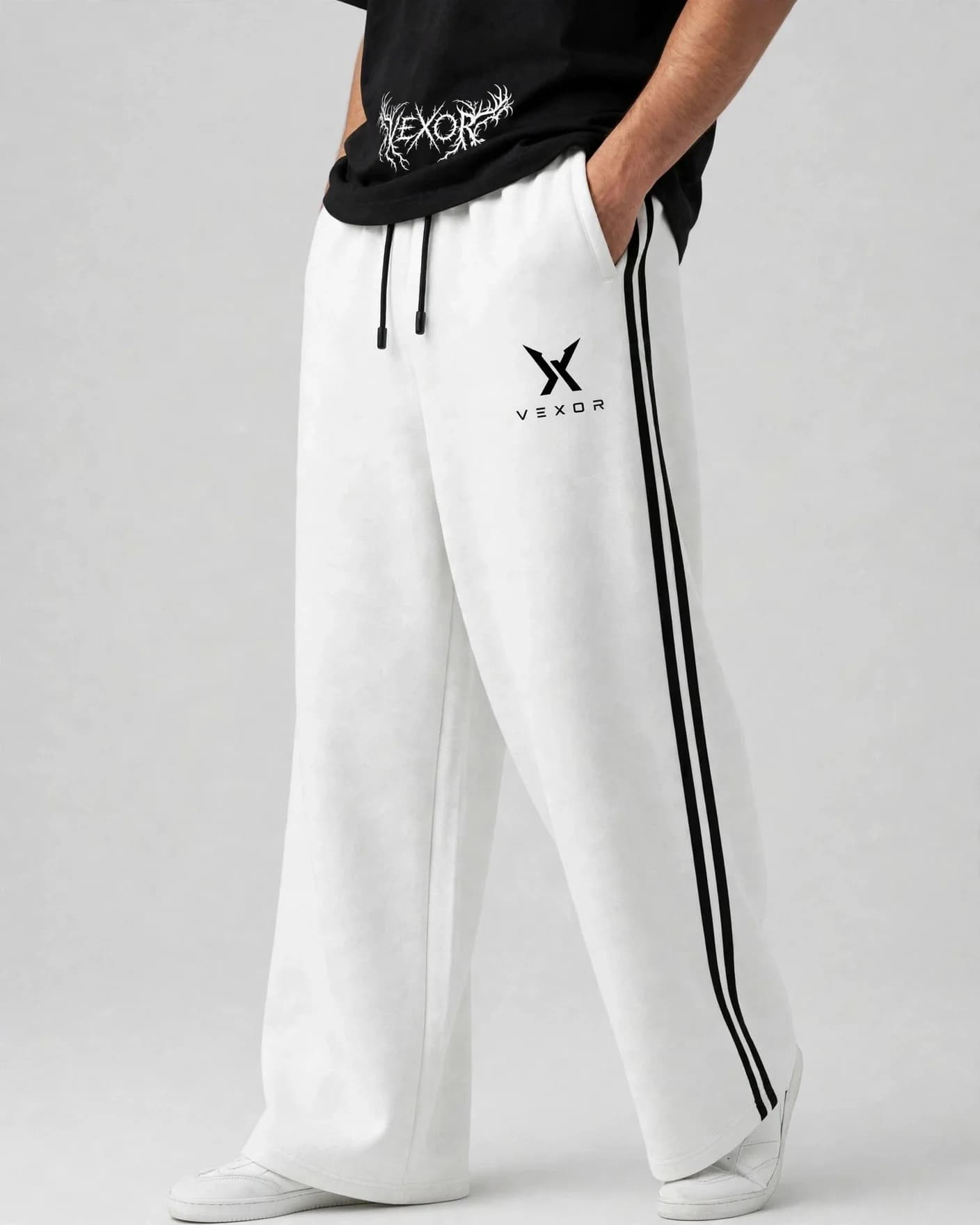 Man wearing white VEXOR double-stripe wide-leg sweatpants with two black side stripes, front view with the small black X logo and VEXOR name on the left thigh