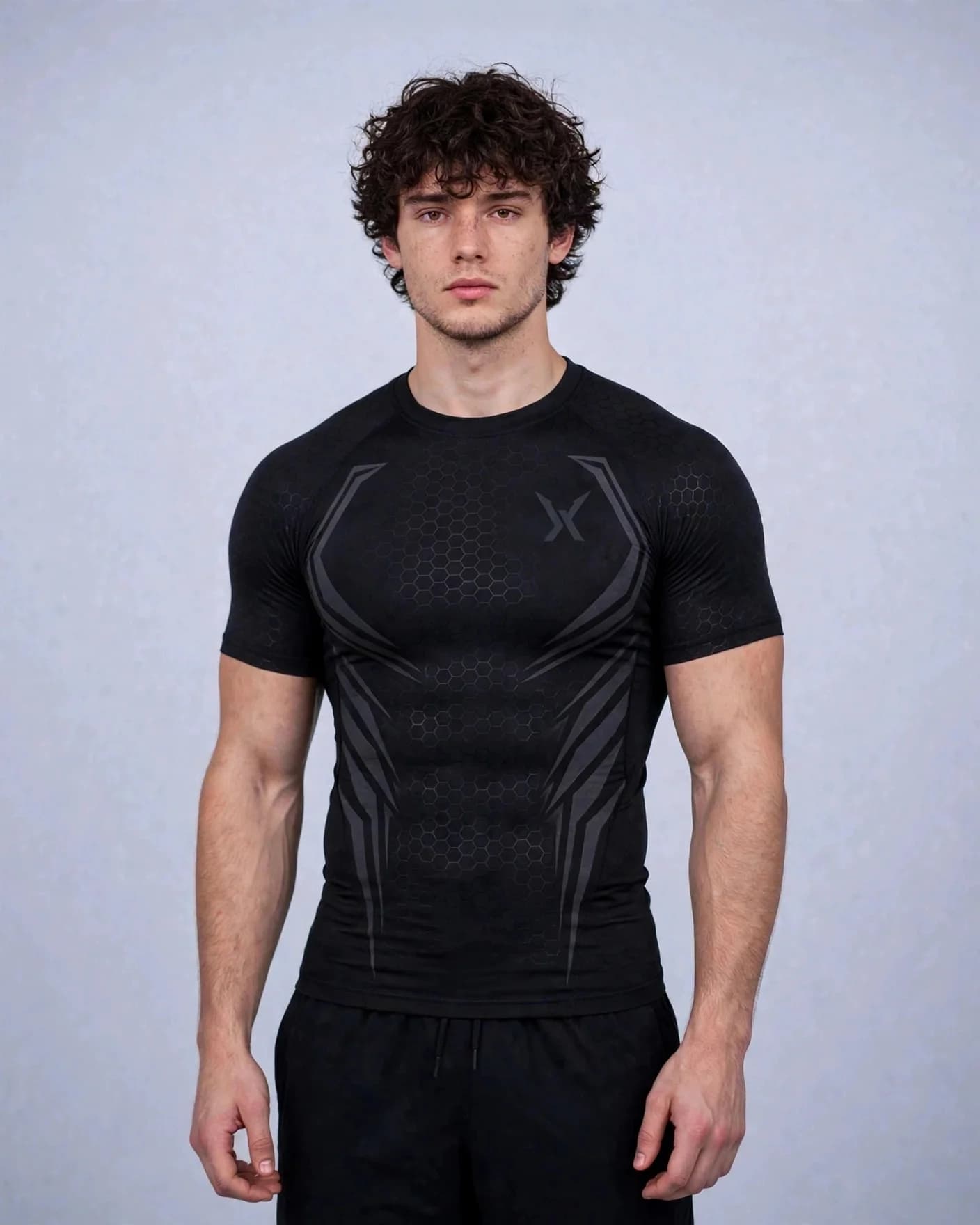 Man wearing the black VEXOR Hex compression tee, front view with dark grey armour lines and a small dark grey X logo on the chest