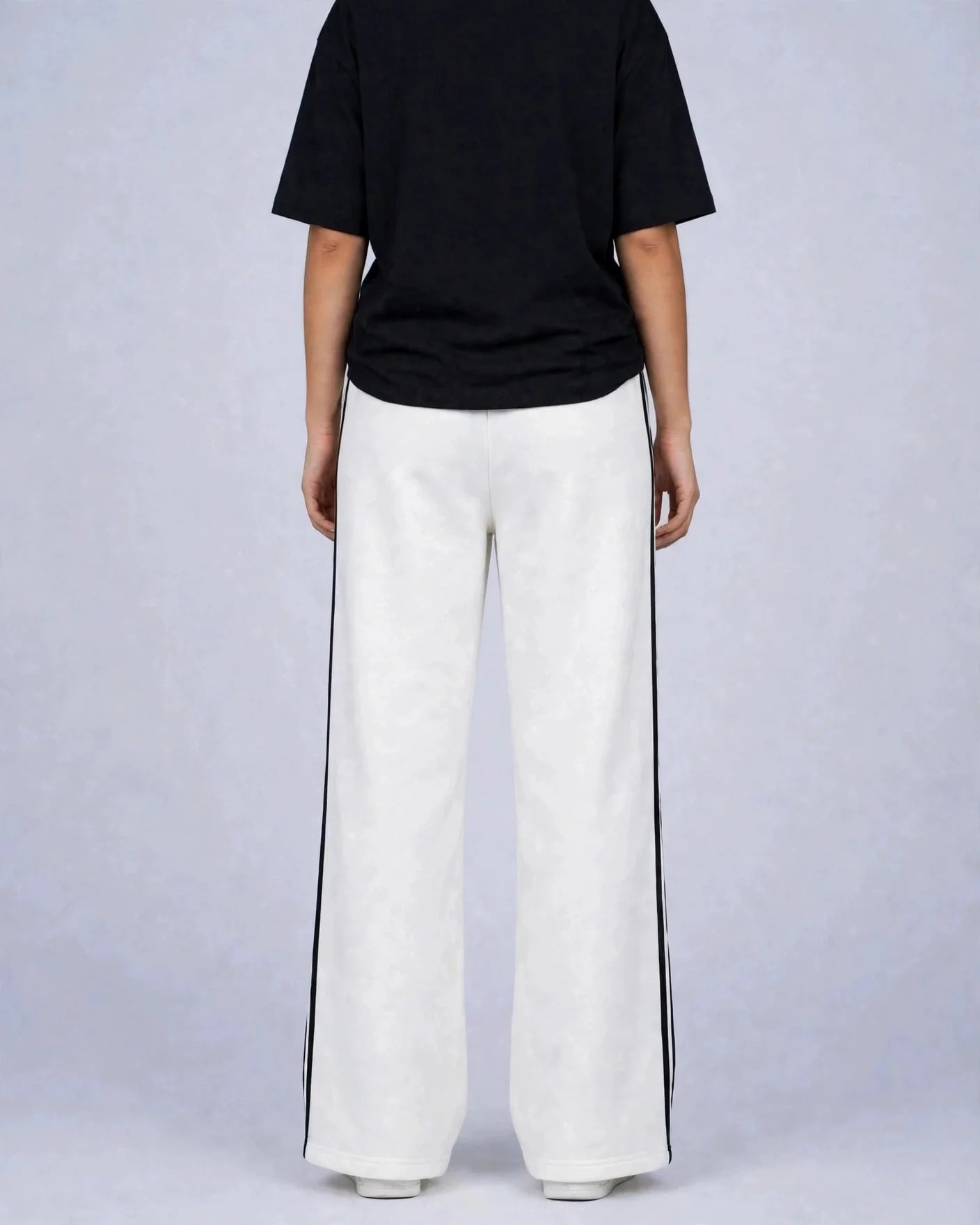 Back view of white VEXOR double-stripe wide-leg sweatpants with two black side stripes on a woman, plain back