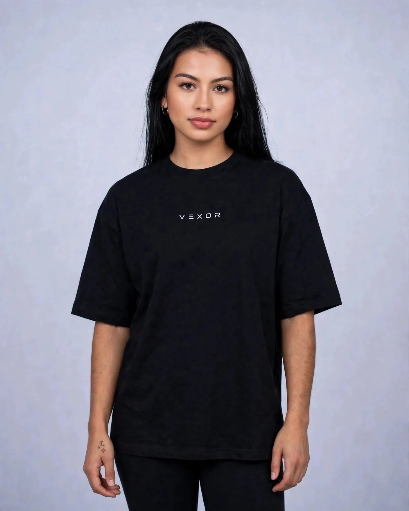 Woman wearing the black oversized tee, front view with the small VEXOR chest logo