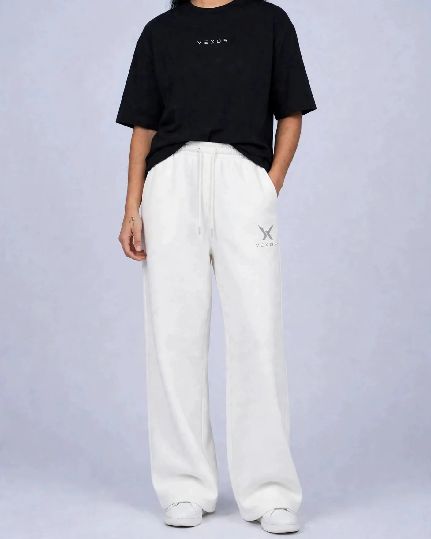 Woman wearing white VEXOR wide-leg sweatpants, front view with the small light grey X logo and VEXOR name on the left thigh