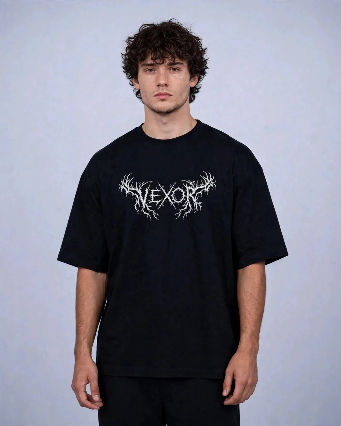Man wearing the black oversized tee with the white thorned metal-style VEXOR logo on the chest
